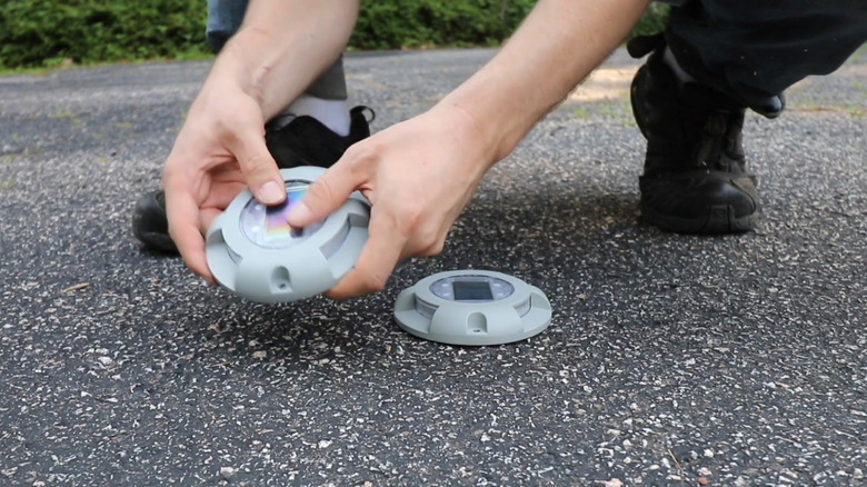 A man installing puck lights into asphalt driveway