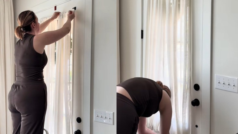 Woman hanging and fastening sheer French door glass window curtains on rod