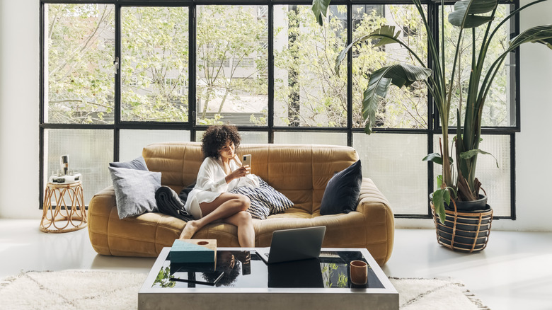 Woman on sofa in front of window in large open living room