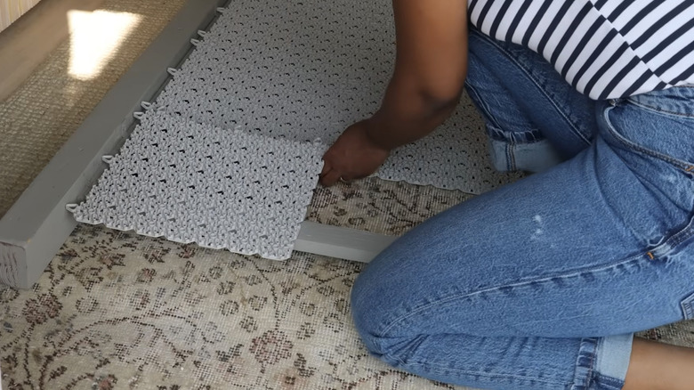 woman making a balcony privacy screen made with IKEA ALTAPPEN perforated decking tiles inside a painted wood frame