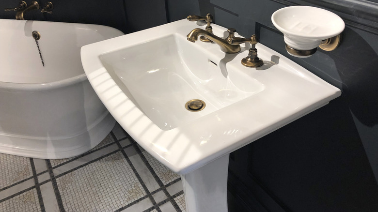 A white pedestal sink beside a bathtub