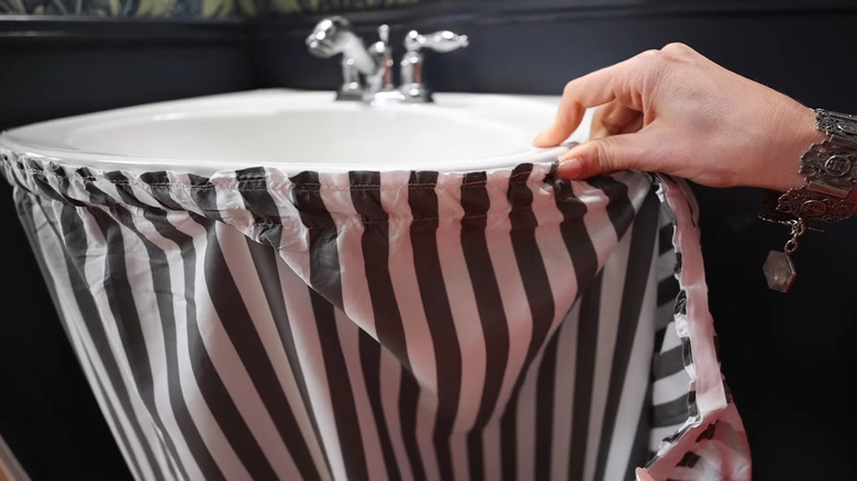 Woman installing adhesive curtains on a pedestal sink