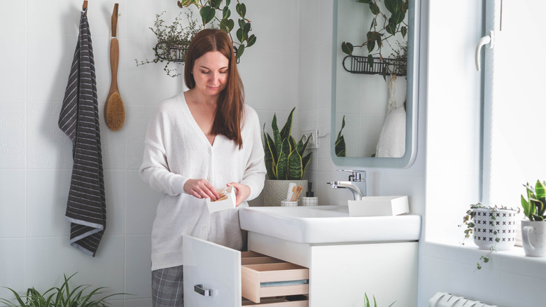 A person organizing a bathroom vanity