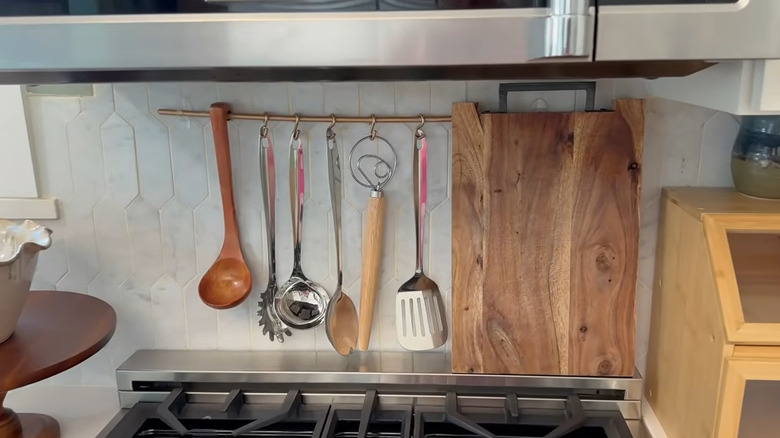 DIY hanging system in the kitchen using a dowel, S hooks and self-adhesive hooks with utensils hanging on it