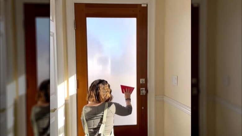 Woman smoothing out reeded cling film on a glass front door