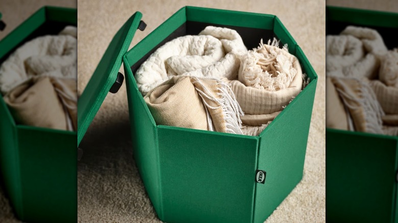 IKEA KJUGE Pouf in green used to store blankets.