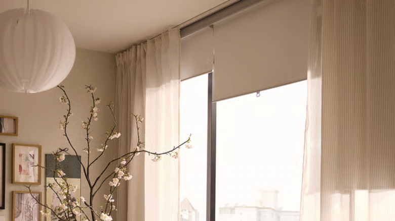 A living room with neutral decor and sheer striped BYMOTT curtains with blinds in the window