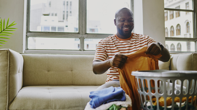 A man smiles as he folds laundry