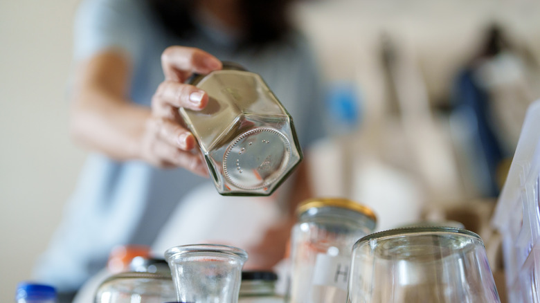woman picking up octagonal jar from a pile of jars