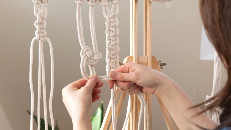 Person making macrame pieces with white rope