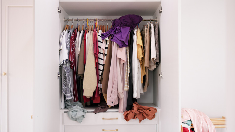 a disorganized and crowded clothes closet