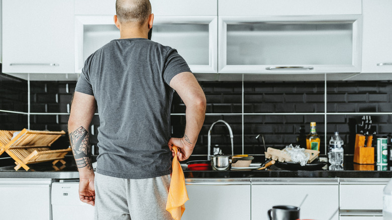 a man stresses out over his cluttered kitchen countertop