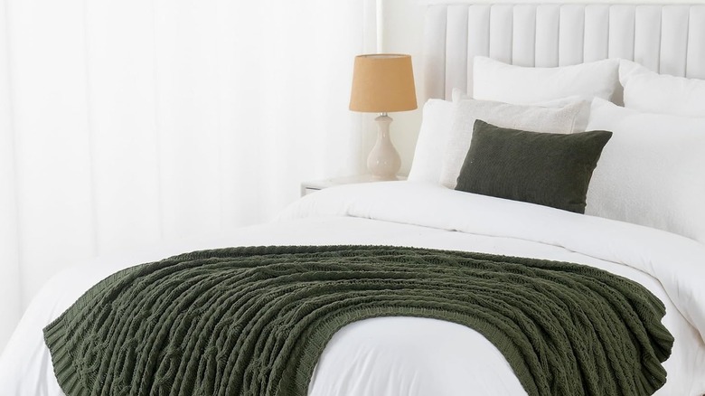 Battilo Throw Blanket in green on a white bed in a white bedroom