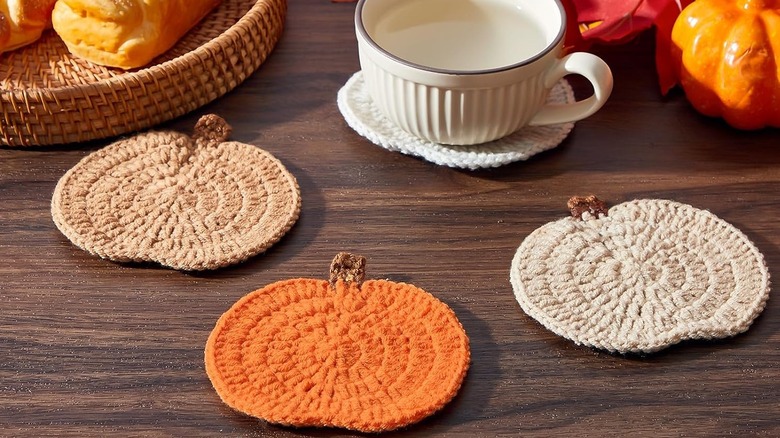 Pumpkin coasters with a cup of tea and autumnal accessories on a wooden table