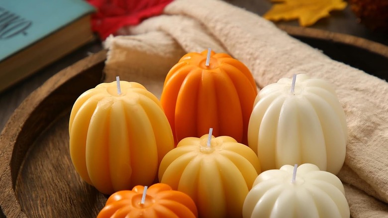 Small pumpkin candles on a decorative wooden plate