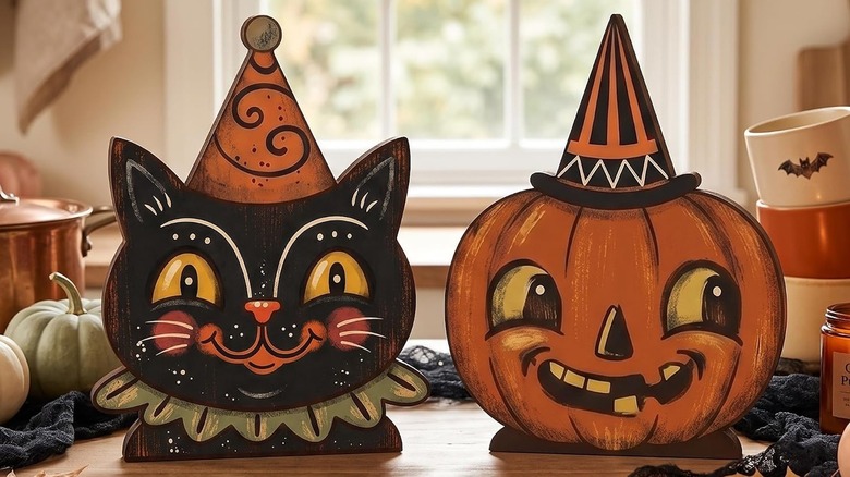Wooden Halloween decor items : a vintage black cat and pumpkin in party hats on a wooden table with fall accessories