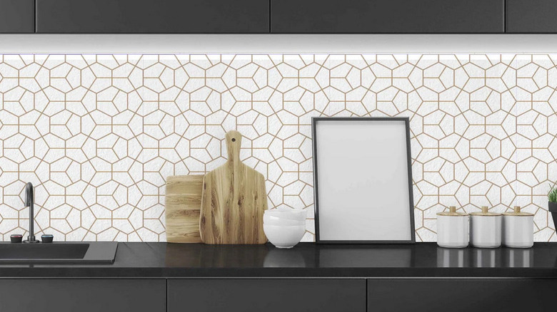 Geometric white and gold art deco backsplash with black kitchen cabinets