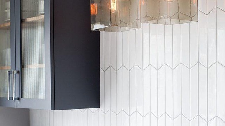 Minimal white tile art deco backsplash with pendant lights and blue cabinets