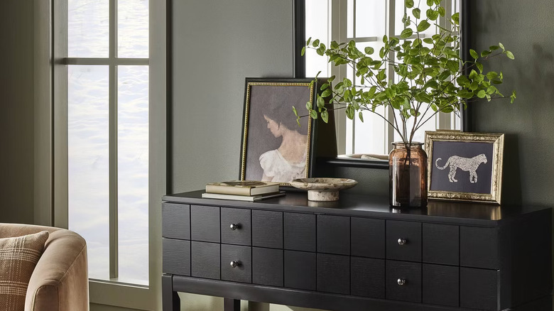 vintage-inspired art pieces layered leaning in front of a mirror on a black console table