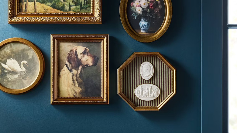 Gallery wall of vintage-inspired artwork on a dark blue painted wall