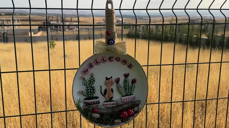 Outdoor decoration made from an old frying pan hanging on a fence