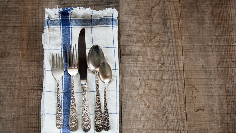 Stieff silverware on a white and blue checkered napkin on a wooden table