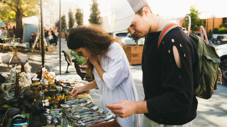 Two young people look at silverware at a vintage market
