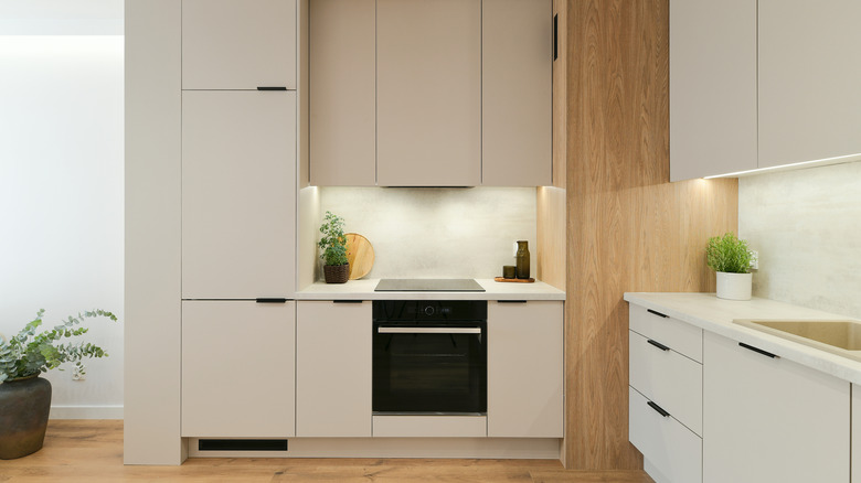 modern kitchen with panel ready fridge to match beige cabinets and a black oven