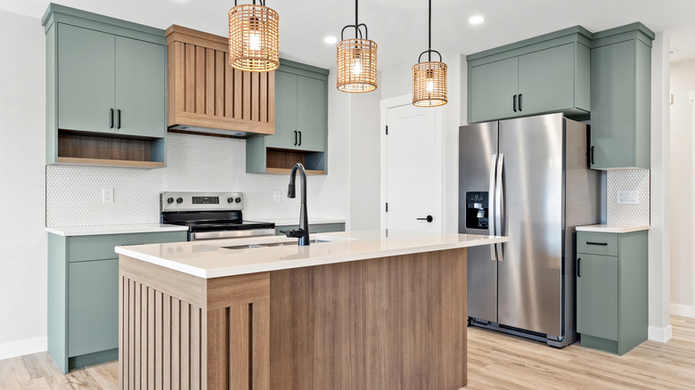 modern organic kitchen with sage green perimeter cabinets, natural wood island cabinets, and stainless steel appliances