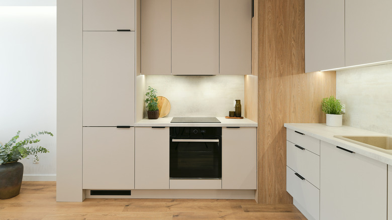 modern kitchen with panel ready fridge to match beige cabinets and a black oven