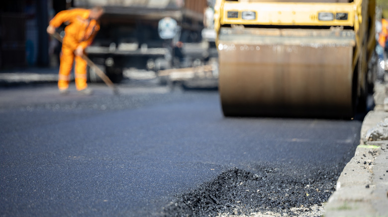 A construction crew paving freshly laid asphalt.