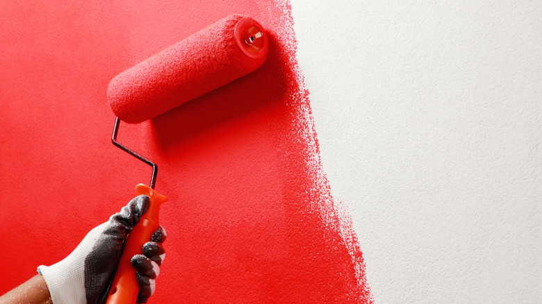 Person painting a wall red
