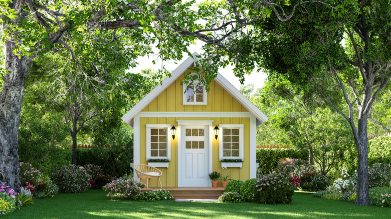 A small house with a front yard filled with trees and shrubs