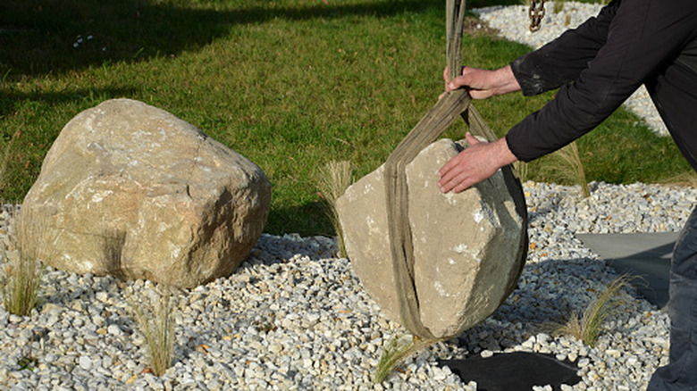 A large rock being placed in a yard to decorate it