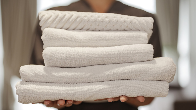 woman holding white bath towels and bath sheets