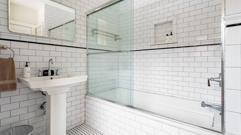 Modern bathroom with white subway tile and sliding glass bathtub doors