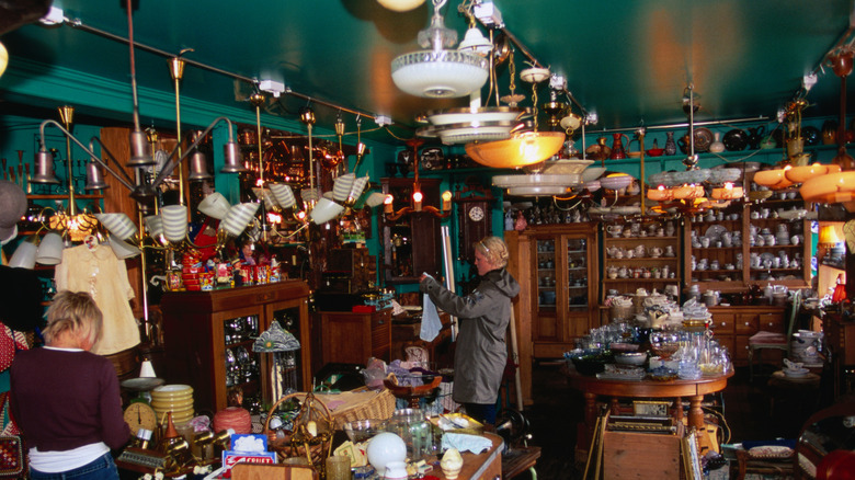 Shoppers browsing antique store with lamps and chandeliers