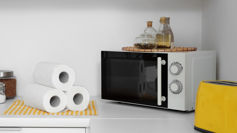 A stack of paper towels next to a microwave