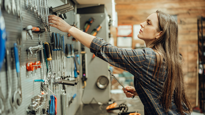 A woman reaches for garage tools