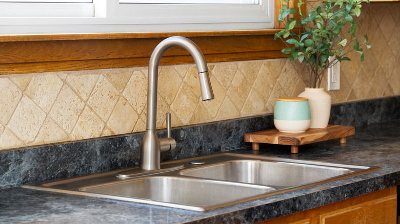 A stone and marble backsplash behind a kitchen sink