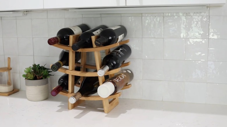 A beautiful white zellige tile backsplash in a kitchen with wine bottles on the counter
