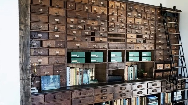 A large antique bookcase with rolling ladder is shown in Joanna Gaines' home