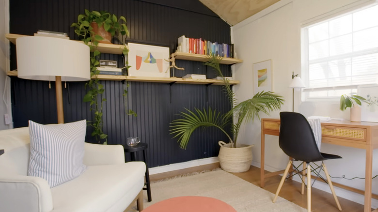 An office features an accent wall covered in navy beadboard