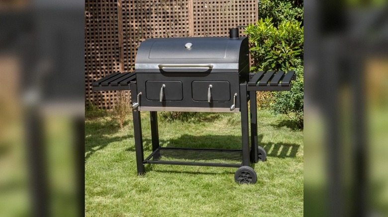 A Captiva Designs 34-inch Barrel Charcoal Grill on grass in a yard