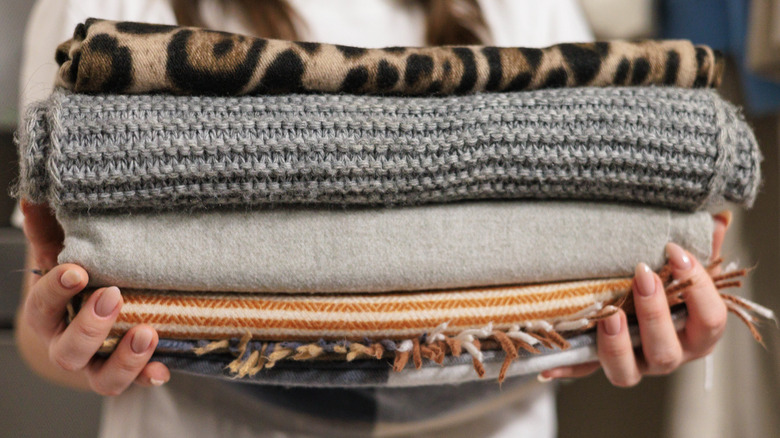 A person holding a stack of blankets