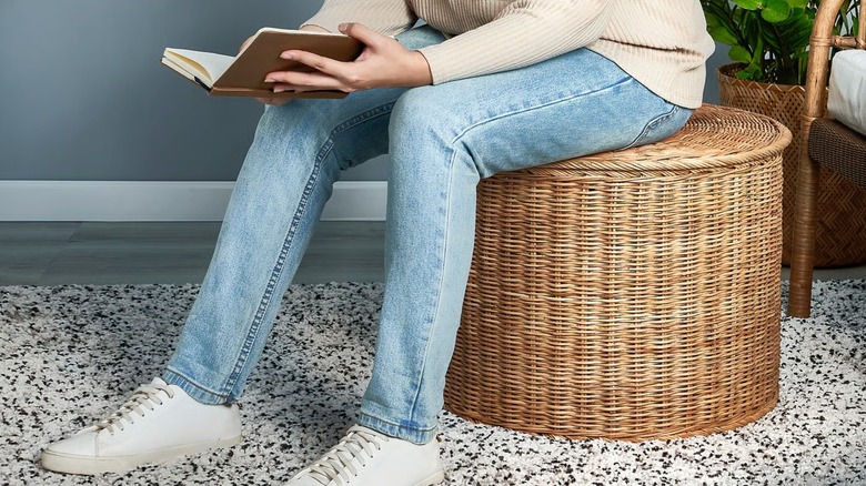 Person reading sitting on TOLKNING Ottoman with storage