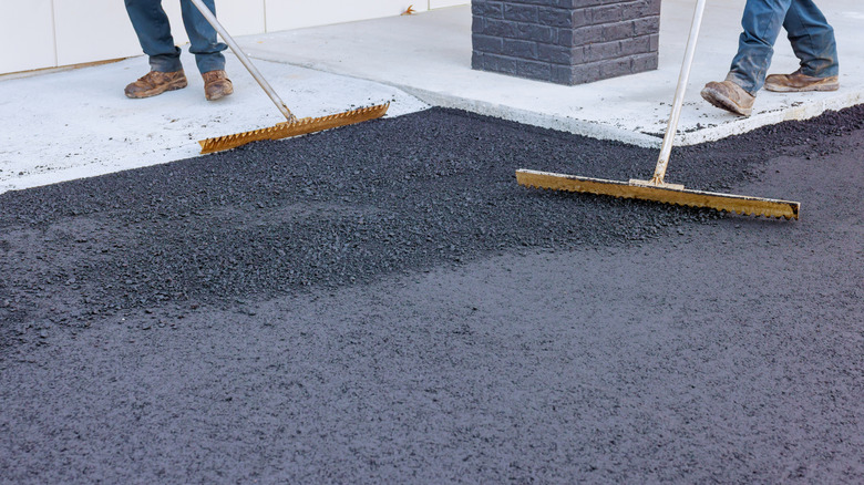 Workers using rakes to level asphalt
