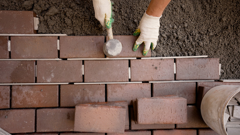 Worker laying bricks for driveway