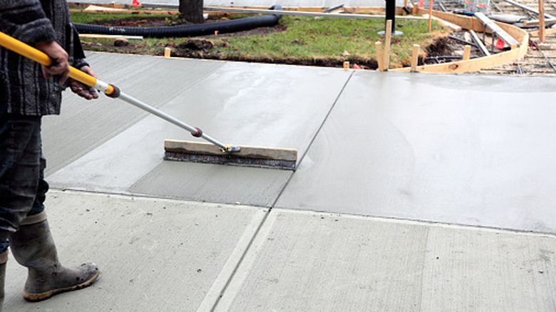 Worker smoothing a poured concrete driveway