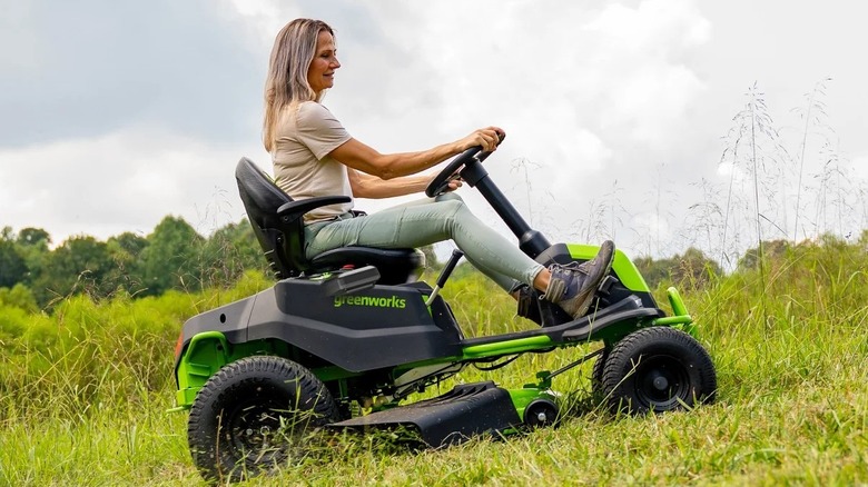 woman driving lawn mower on a grassy hill